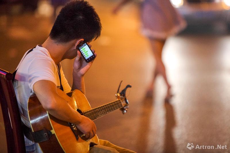 周国献作品：吉他艺人胡志在路旁休息。
