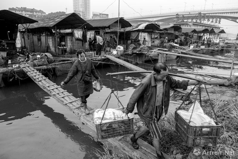 周国献作品：武汉江汉一桥附近水上鱼市的鱼贩挑鱼送到定点餐馆。